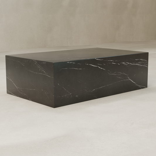 The Obscara Coffee Table, featuring a rectangular marble top with subtle white veining and a marble plinth base, is set on a light floor against a beige wall.