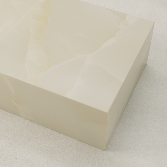 A close-up of the Lunelle Onyx Coffee Table showcases its large rectangular shape and smooth, glossy cream-colored surface with a milky hue and subtle marbled patterns, set on a light textured floor.