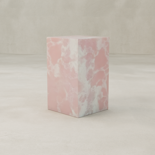 The Cora Tall Plinth, featuring a pink and white marbled texture inspired by Pink Onyx designs, stands on a smooth light beige floor with a matching beige background.