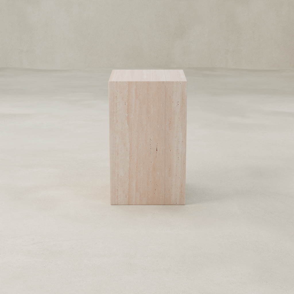 The Alessia Tall Plinth, a rectangular travertine stone pedestal, stands on a smooth, light-colored floor against a neutral, textured background.