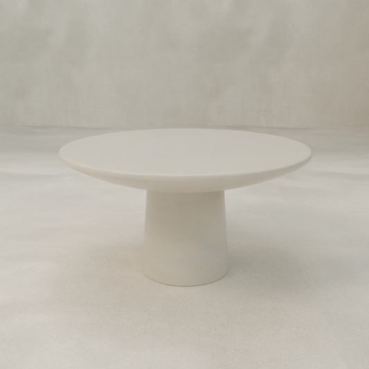 The Arrio Table is a minimalist, modern circular table in white with a sleek, thick broad base, shown against a light textured background.