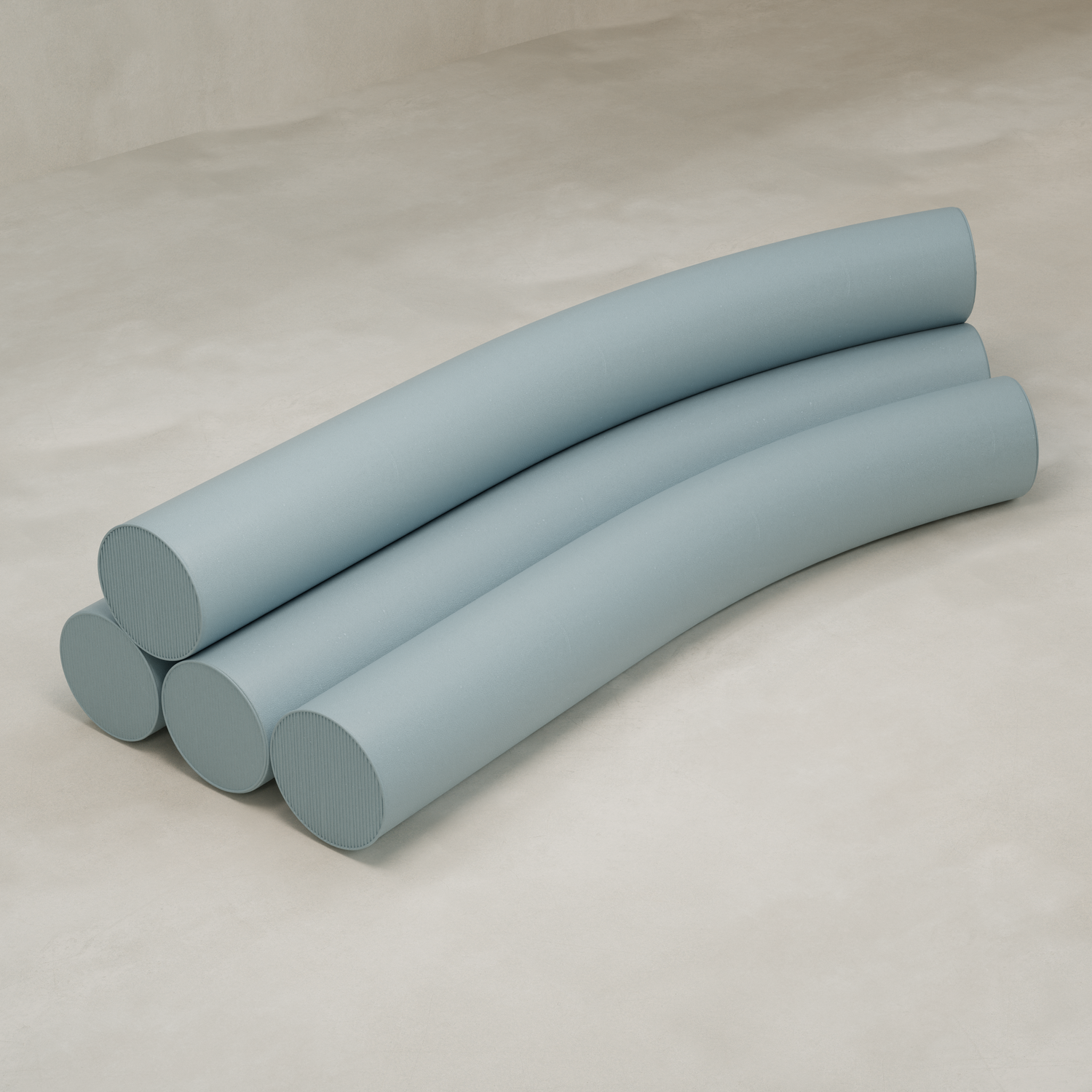 Four long, light blue cushions are stacked in two layers on a beige surface, each slightly arched and aligned side by side, resembling the soft forms of the Cylindra Sofa.
