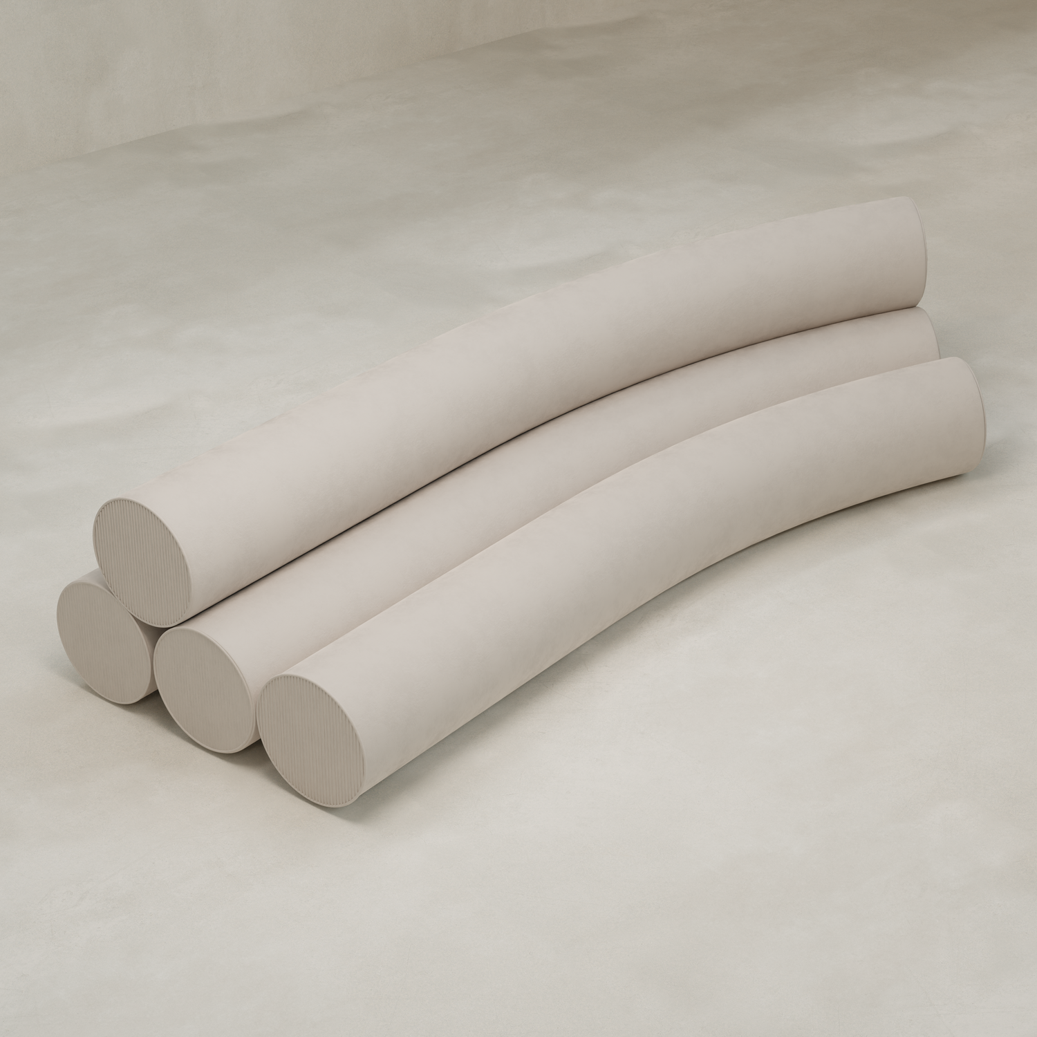 Four large, light beige cylindrical cushions, part of the Cylindra Sofa, are stacked in a staggered wave-like arrangement on a smooth neutral floor, evoking playful neotenic forms.