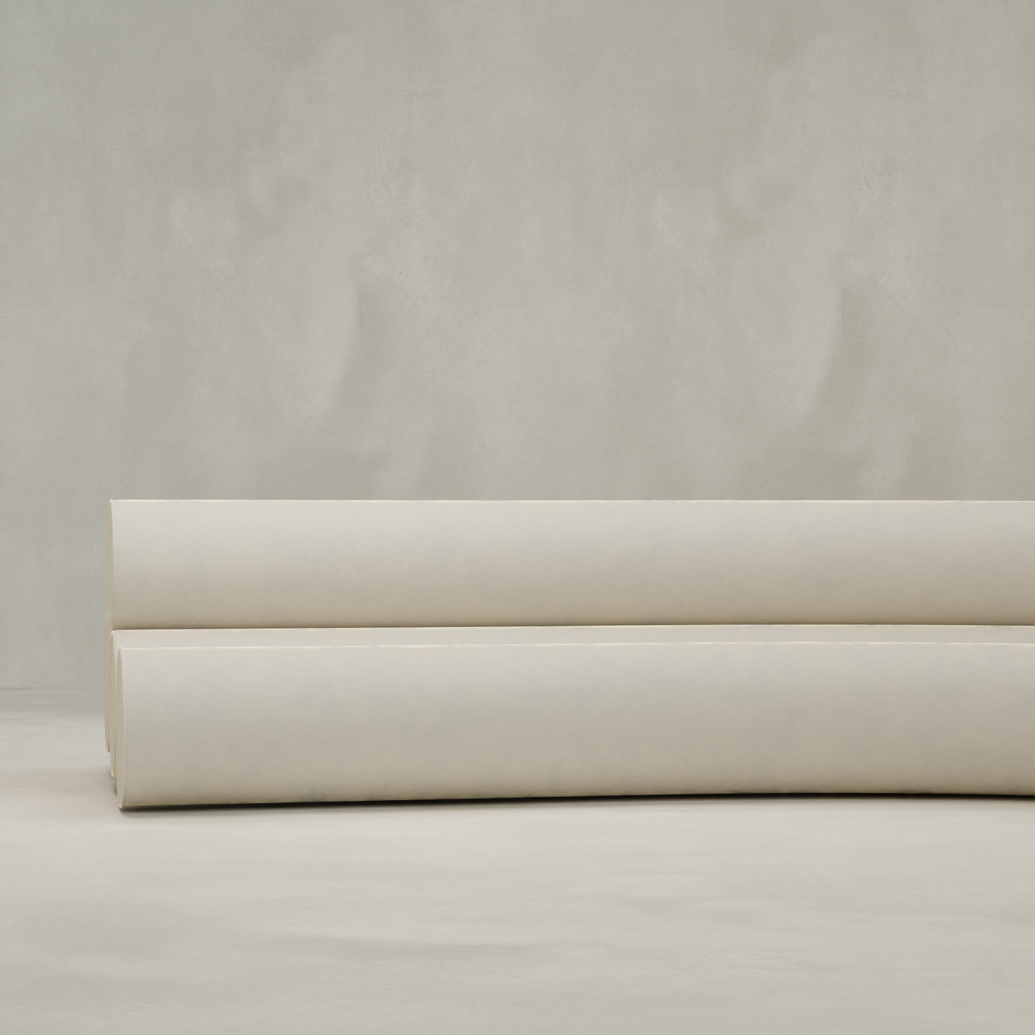Two large rolls of light beige fabric rest on a neutral surface—perfect for upholstering a Cylindra Sofa—set against a plain, textured background.