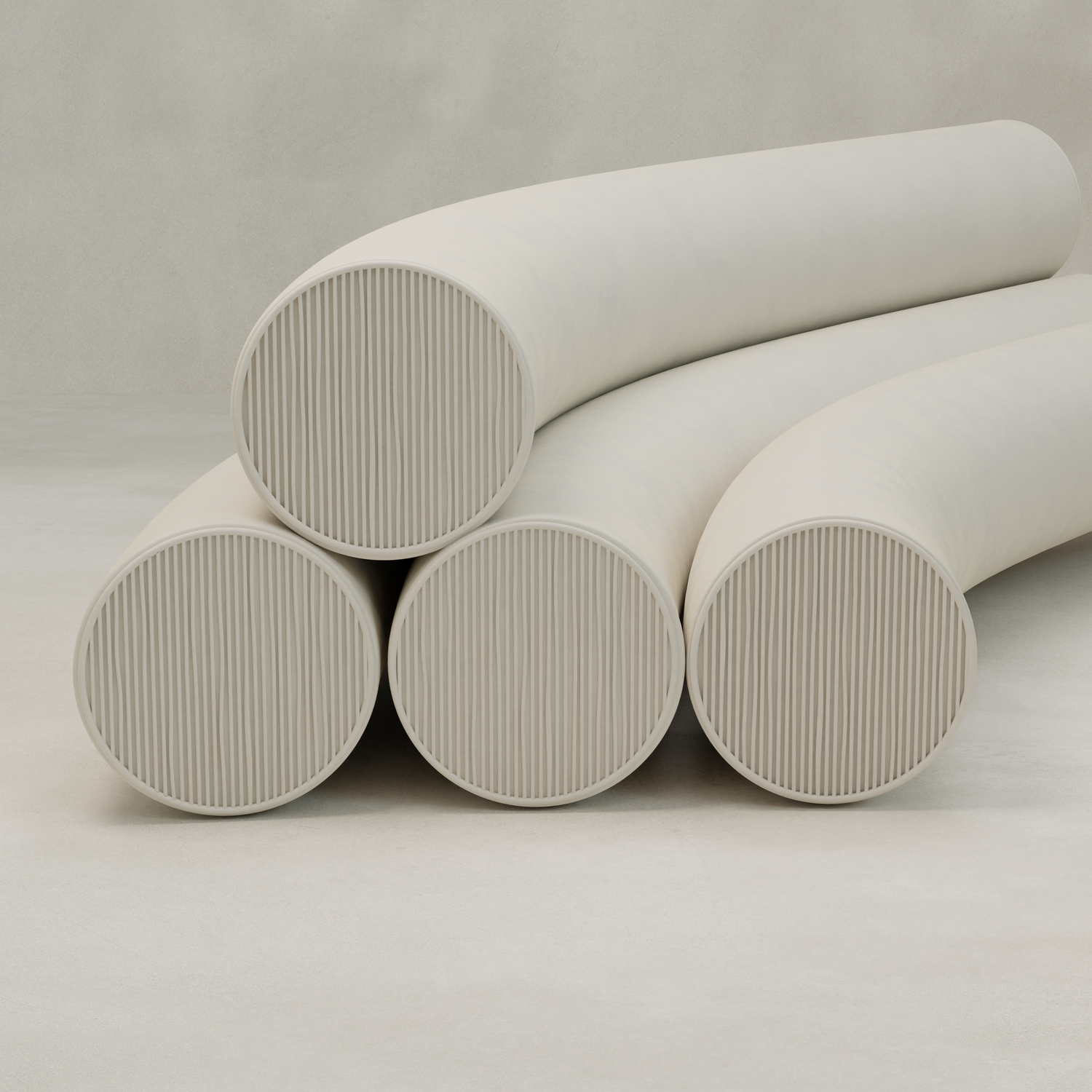 Four large, pale cylindrical forms with ribbed ends—three as the base and one curved on top—are stacked on a smooth surface against a plain background, showcasing the modern Cylindra Sofa’s distinctive neotenic-inspired design.