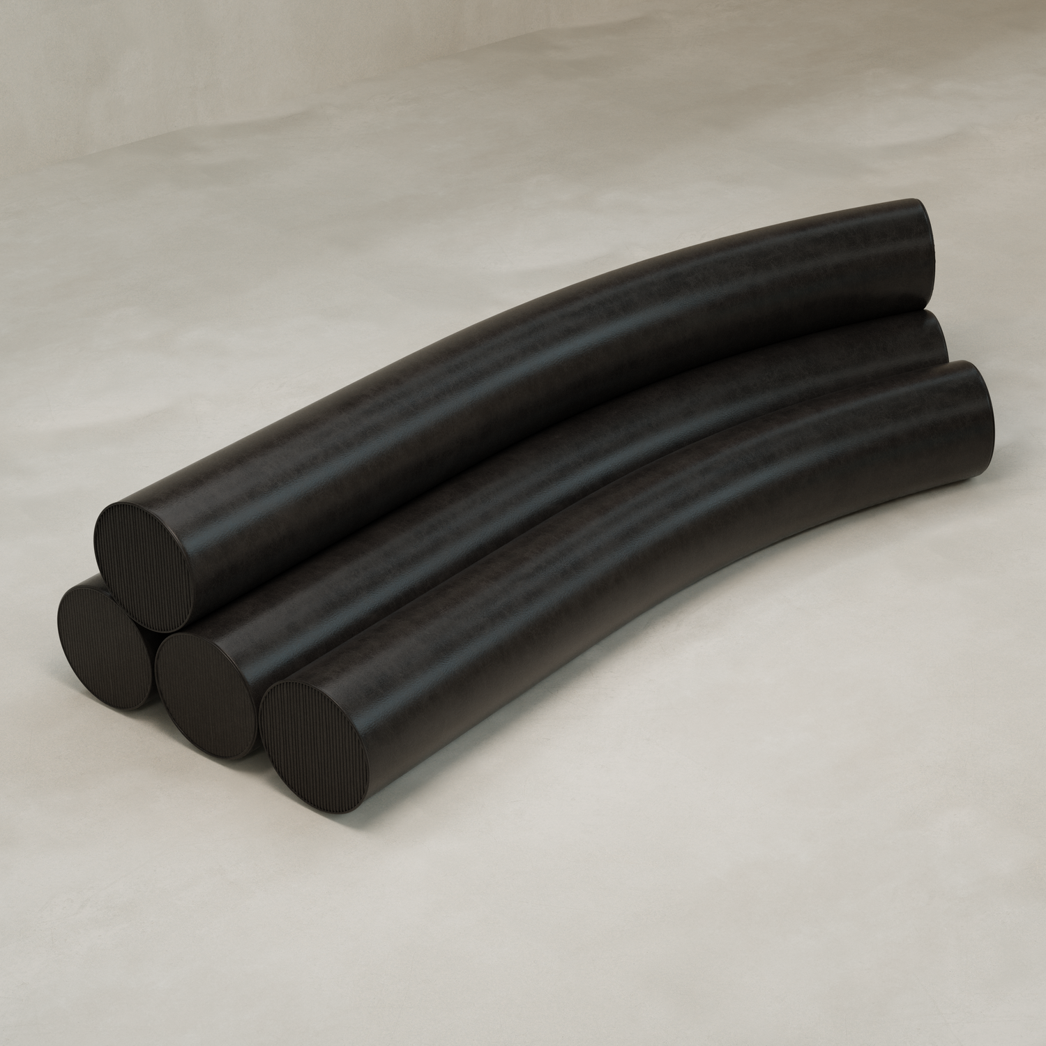 Four black cylindrical sections of the Cylindra Sofa are stacked on a smooth, light surface. Three form the base while one rests on top in an arch, creating a modern sofa silhouette against a plain background.