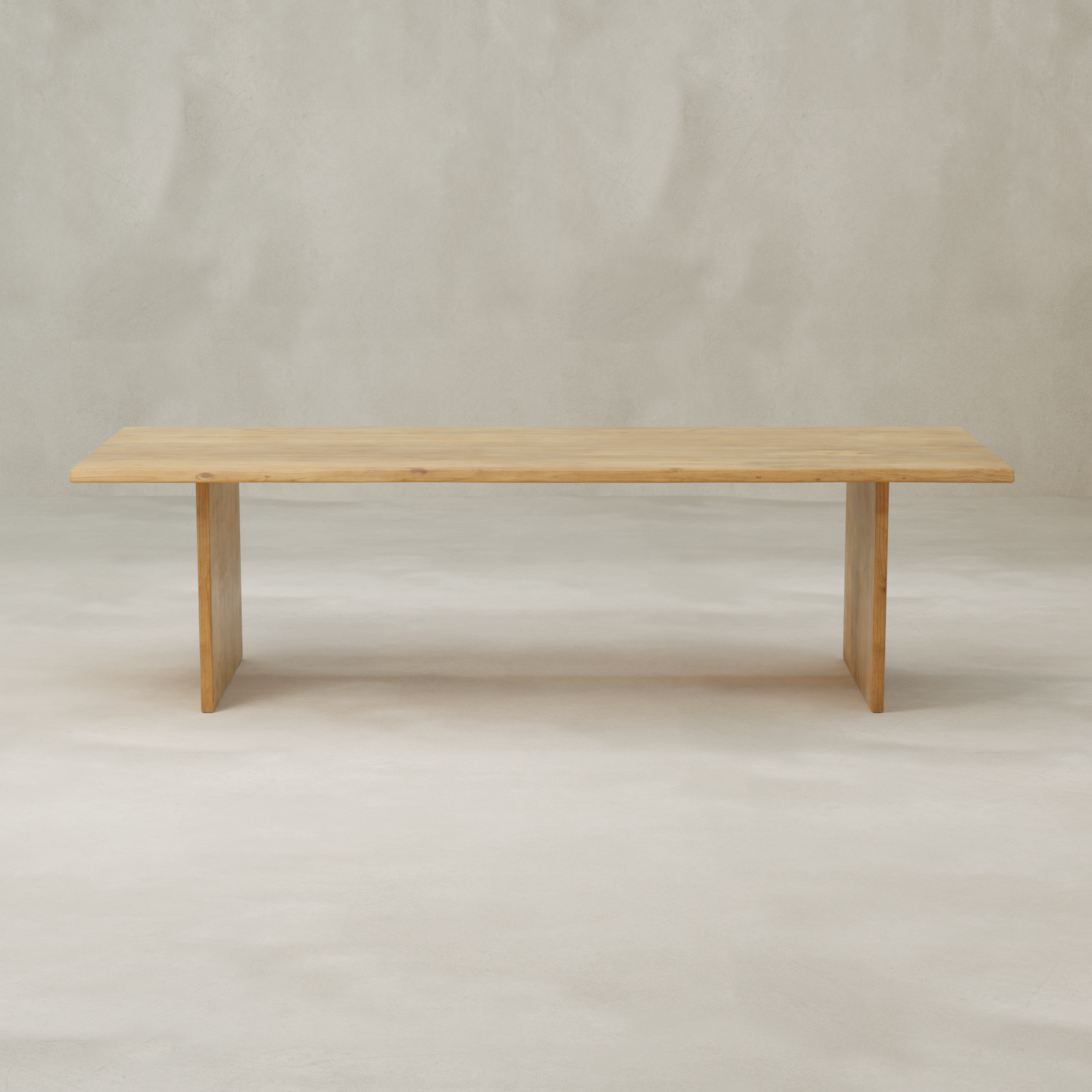 The Elm Farmhouse Table is a simple rectangular dining table made from aged Elm, with clean lines and two wide flat legs, shown against a light neutral background.