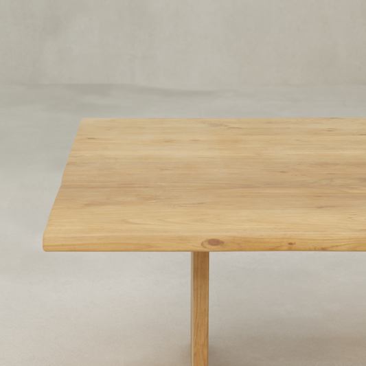 A close-up of the Elm Farmhouse Table Large showcases its rustic charm with a natural finish on aged Elm. The tabletop and a leg stand out against a plain, light-colored background.
