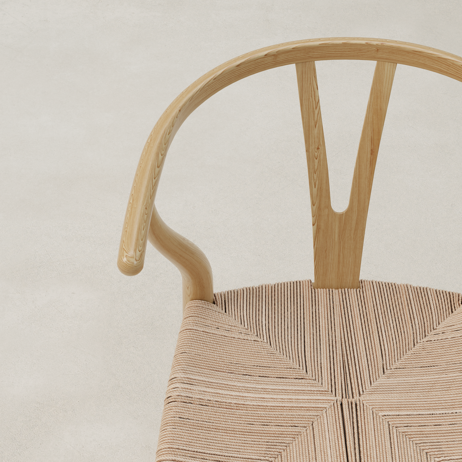 A close-up of the Elsa Chair, featuring a curved Y-backrest and woven seat, viewed from above on a light, textured surface—perfect for pairing with a farmhouse dining table.