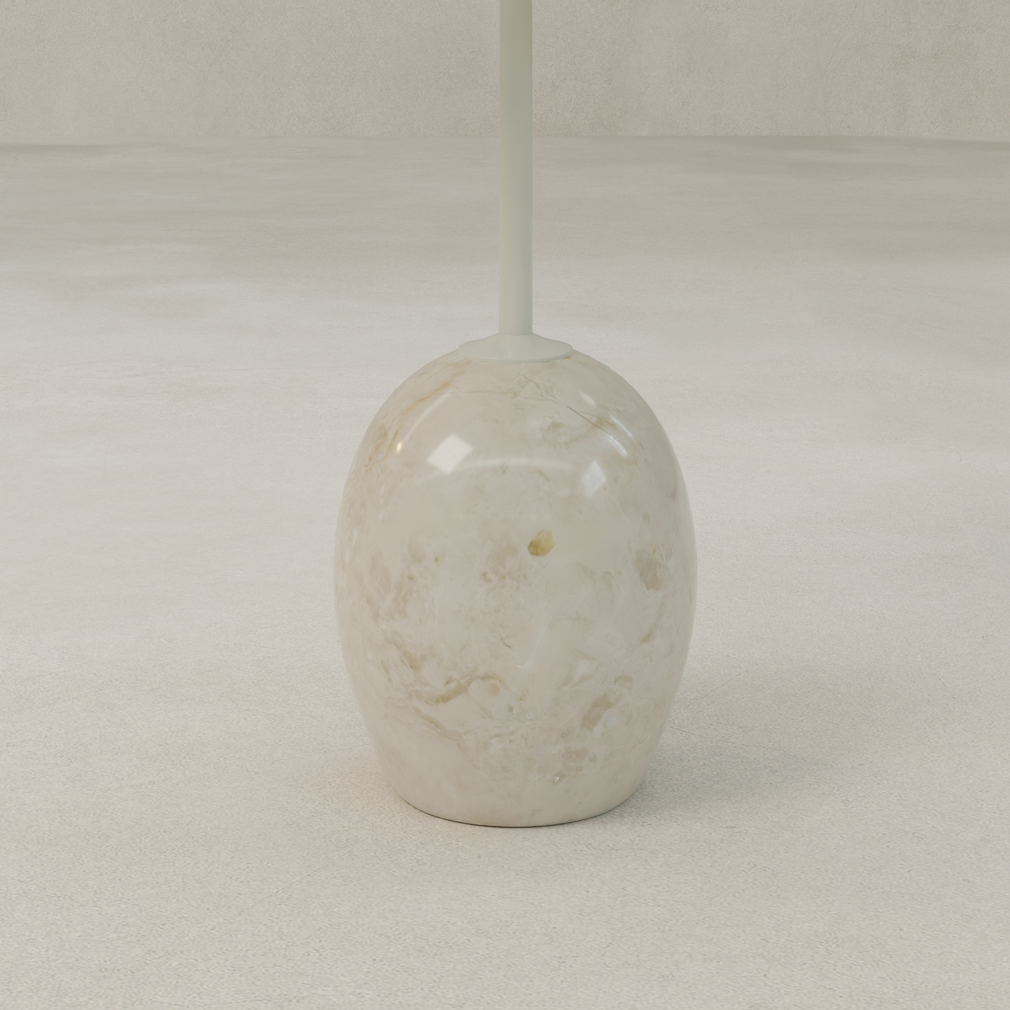 A marble-patterned toilet brush holder with a rounded, glossy base and white handle is stylishly placed on a light surface beside the contemporary Le Folie Table Crema Tall, which features a striking stone leg.