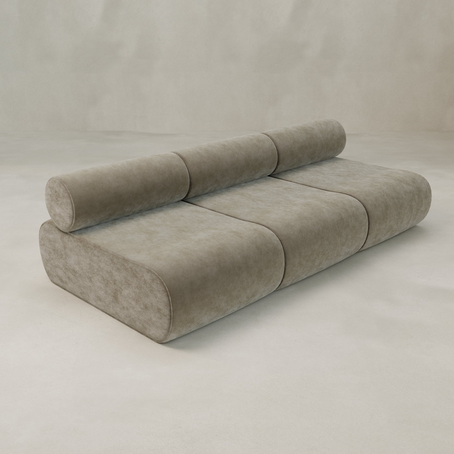 The Nuage Three Seater Modular Sofa showcases a modern, minimalist design with soft light brown fabric, rounded edges, three seat sections, and a cylindrical backrest along its length, set against a neutral background.