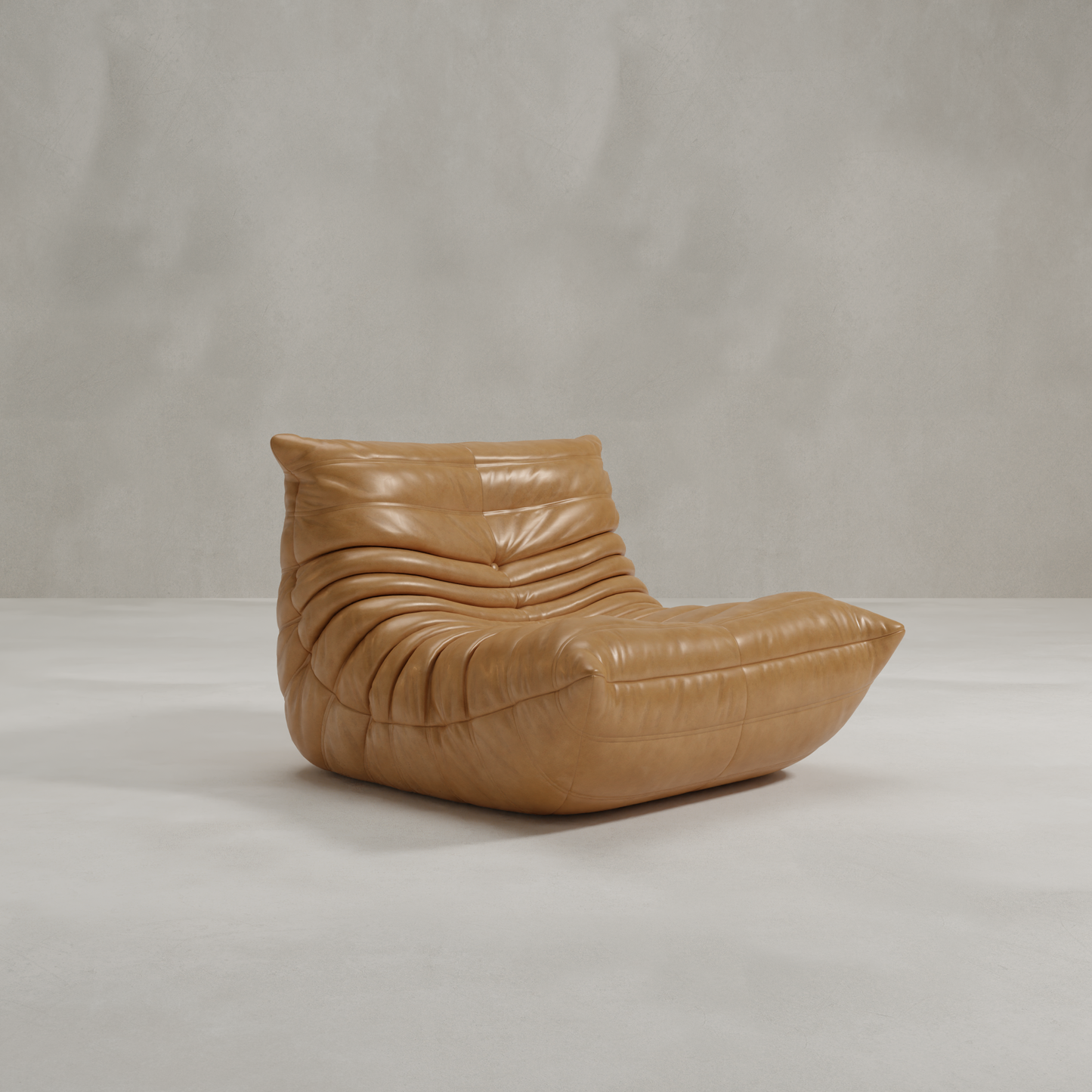 The Rolo Lounge Chair, a modern low-profile lounge chair in tan leather with plush tufting and mid-century style, sits on a smooth light gray floor against a textured gray wall.