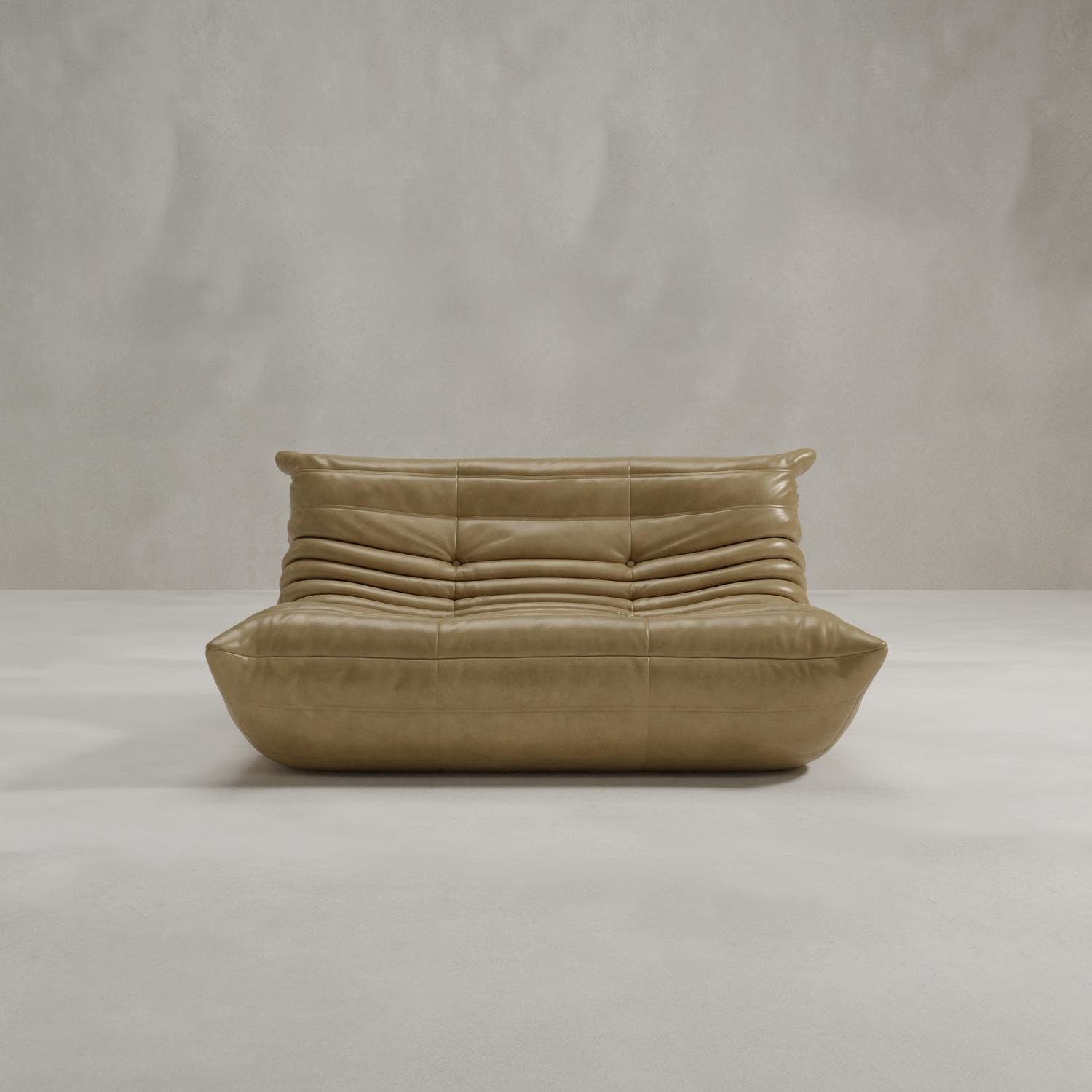 The Rolo Lounge Loveseat, a modern low-profile tan leather seat with plush horizontally-stitched cushions, is placed in a minimal light-gray room with mid-century design elements and a smooth concrete floor against a textured wall.