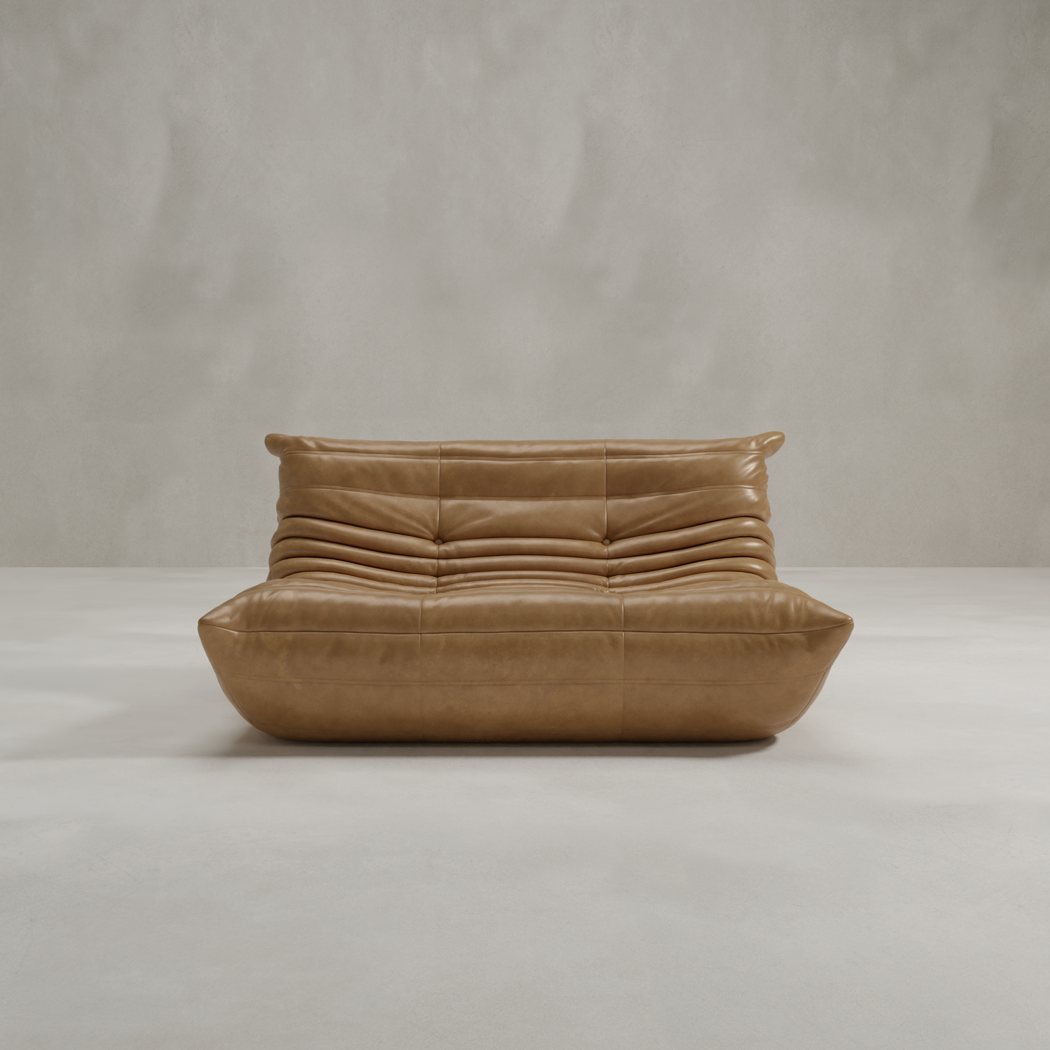The Rolo Lounge Loveseat is a modern tan leather sofa with a low profile, rounded edges, and horizontal tufting that channels mid-century design, set against a plain light gray wall and floor.