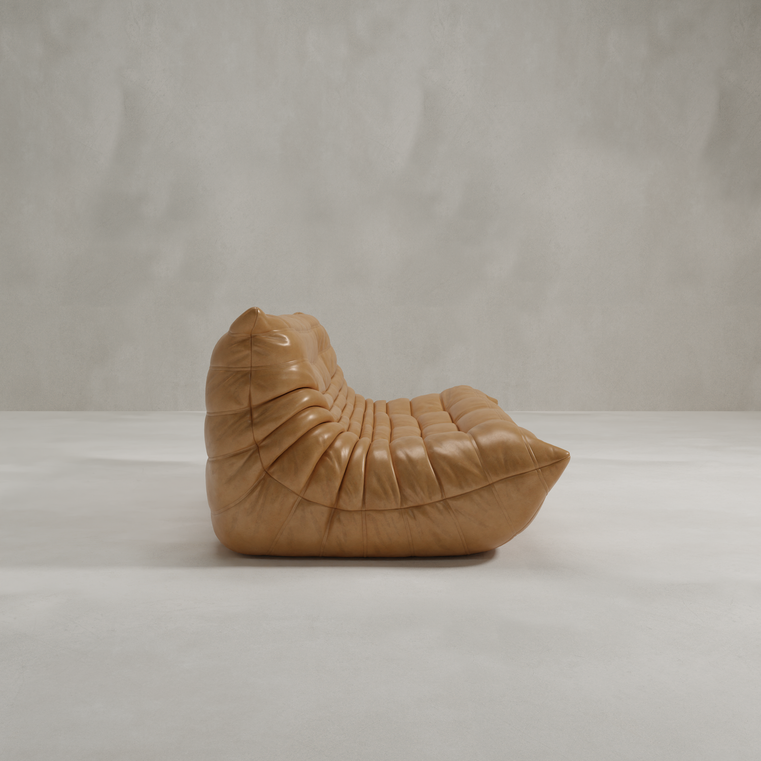 The Rolo Lounge Three Seater features tan, ruched leather upholstery and a modern low-profile silhouette inspired by mid-century and 70s lounge design, perfect for minimalist, light-gray spaces.