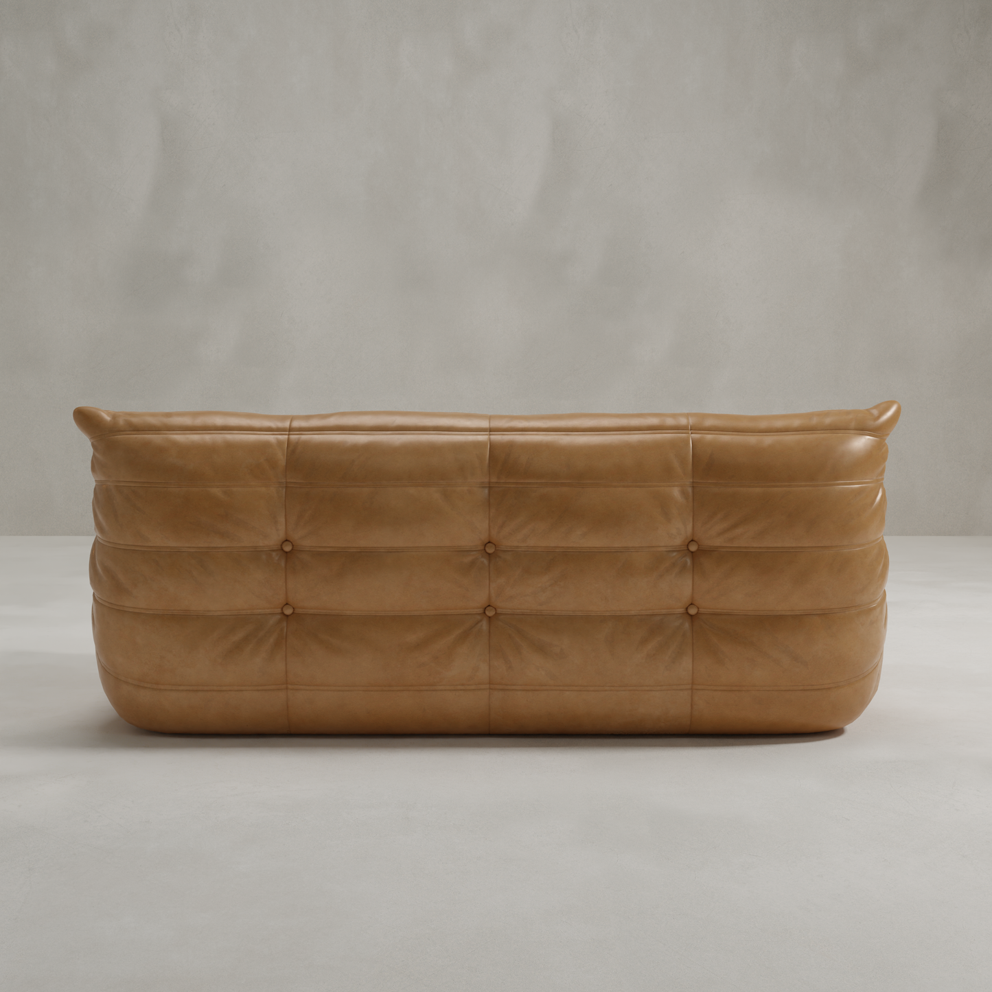 The Rolo Lounge Three Seater, a tan leather tufted sofa with rounded edges and button details, sits against a light gray wall for a minimalist, modern look with mid-century design flair.