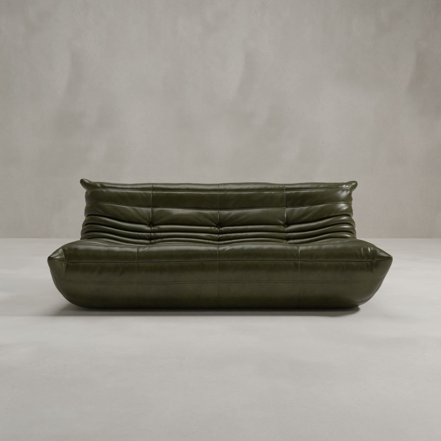 The Rolo Lounge Three Seater, a modern dark green leather sofa with deep horizontal tufting and a low, rounded silhouette inspired by mid-century design, sits against a plain light gray wall and floor.