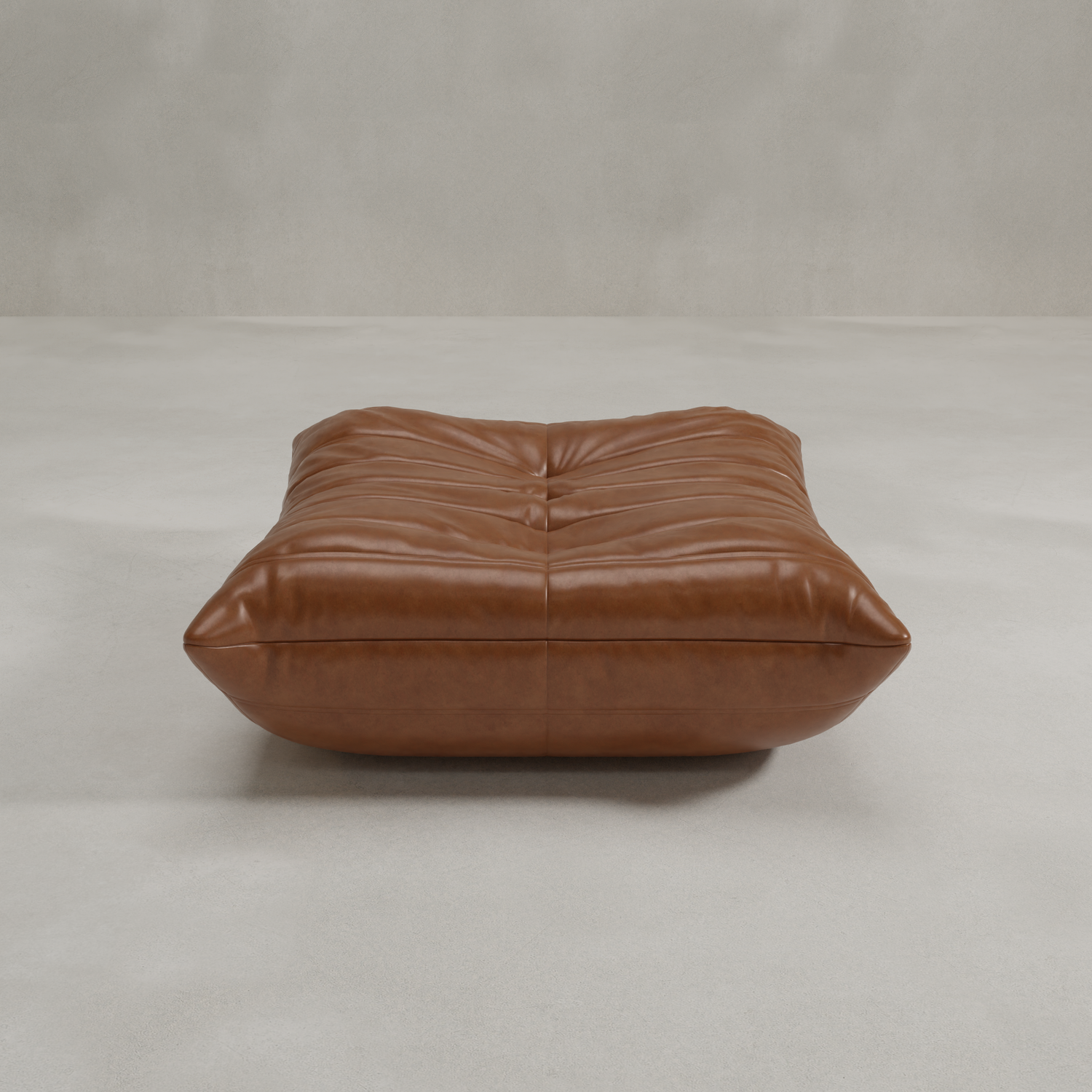 The Rolo Ottoman is a large, low, rectangular brown leather piece with deep tufting that functions as a versatile ottoman or footstool, positioned on a light gray floor against a plain, light-colored wall.