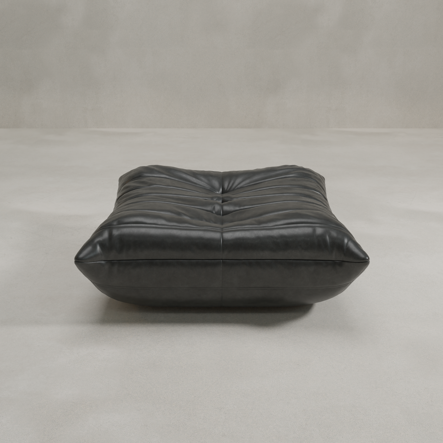 The Rolo Ottoman, a low black leather piece with a tufted cushioned top, sits on a light gray floor against a plain, textured wall.