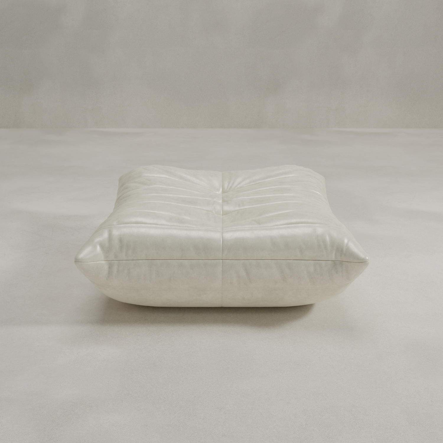 The Rolo Ottoman is a low, square, light gray floor cushion with soft tufted detailing, perfect for extra seating or use as an ottoman in any neutral space.