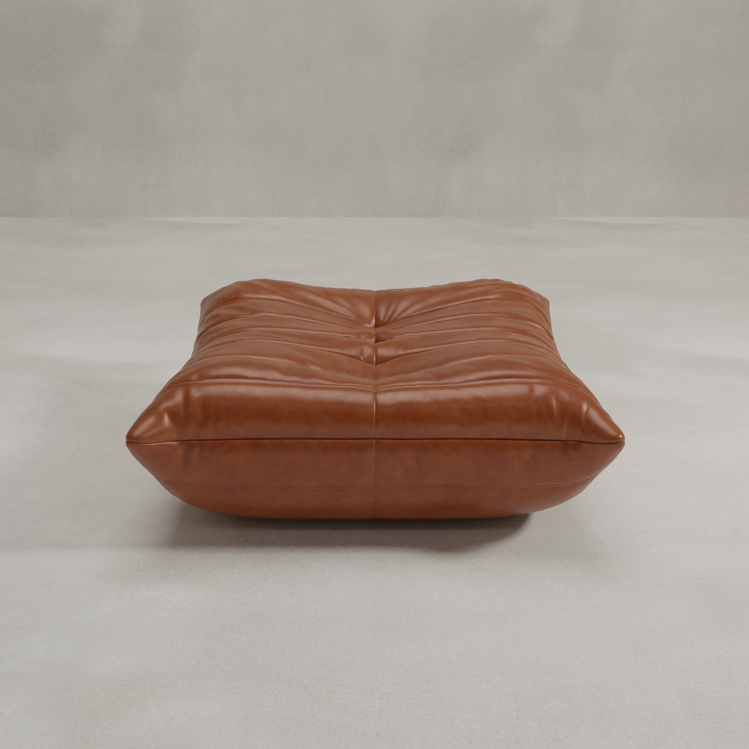 The Rolo Ottoman is a large, rectangular brown leather floor cushion with tufted details, perfect for extra seating or as a cushioned footstool, shown on a light-colored, minimalistic floor and background.