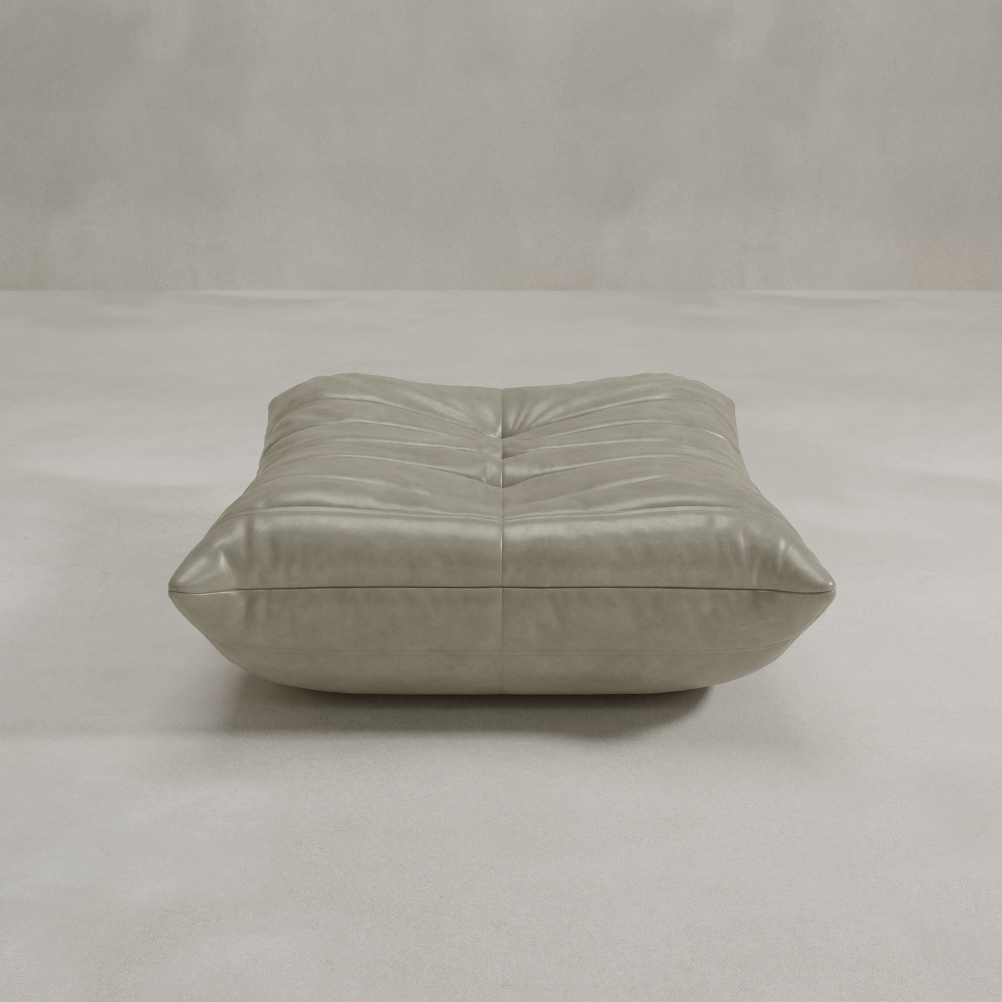 The Rolo Ottoman is a modern, low-profile square gray leather ottoman with soft tufted details, serving as versatile seating or a footrest, shown against a plain, light background.