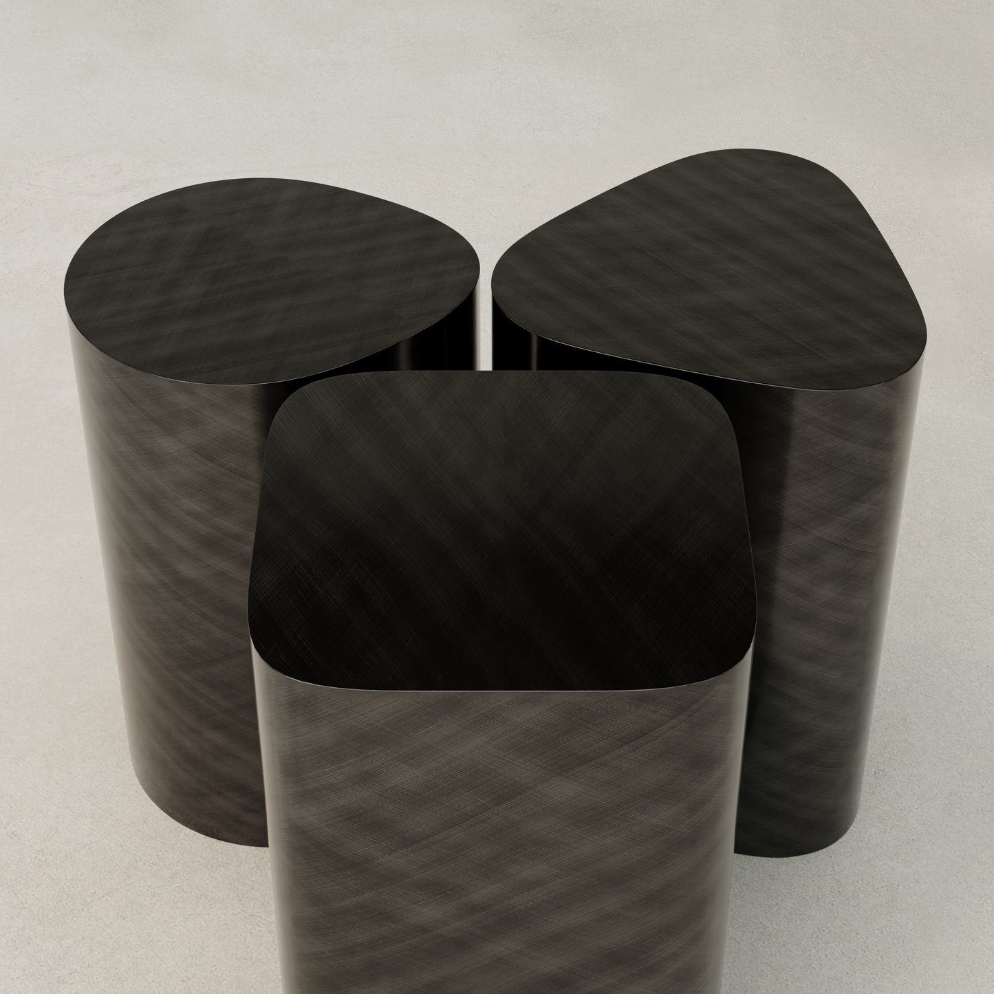 The Set of Solaris Side Table features three dark, metallic geometric stools—triangular, oval, and rounded square—grouped on a light floor, highlighting modern luxury and minimalist design.