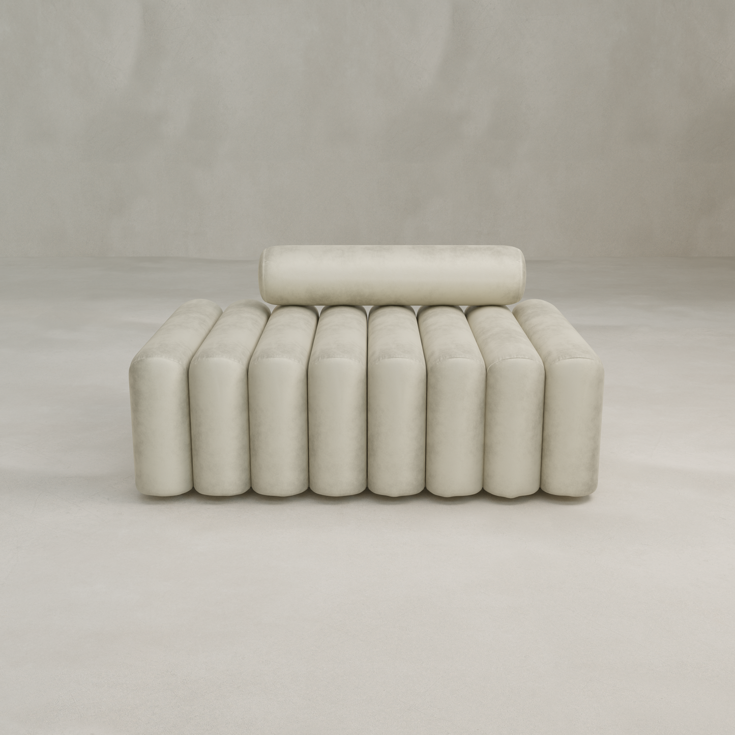 The Sonorra Bench Medium, featuring plush seating and cylindrical cushions in soft light beige fabric, sits against a plain, light-colored wall in an empty room.