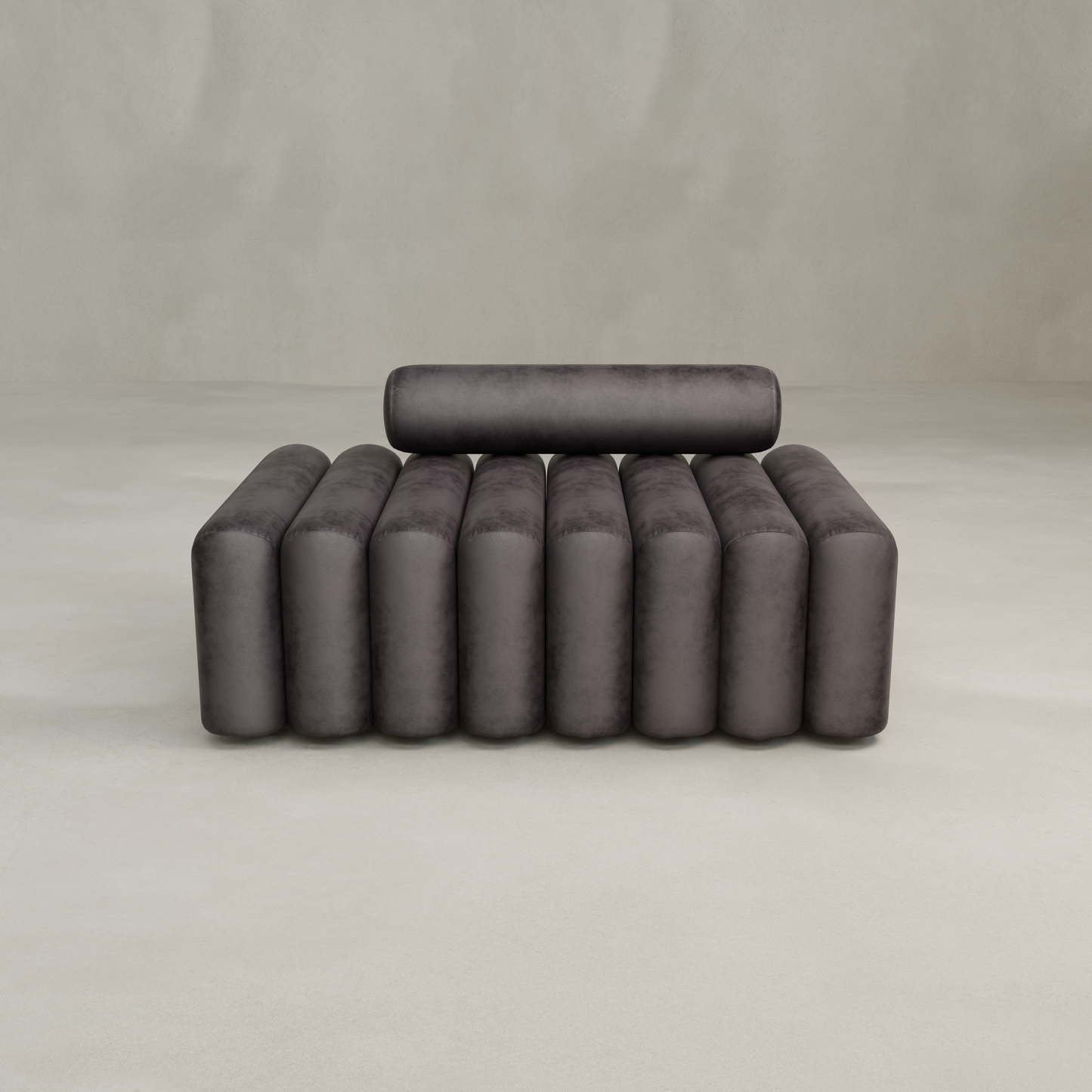 The Sonorra Bench Medium is a modern, dark gray bench with a cylindrical backrest and armrests, boasting plush seating and a ribbed, tube-like design, set against a plain, light-colored background.