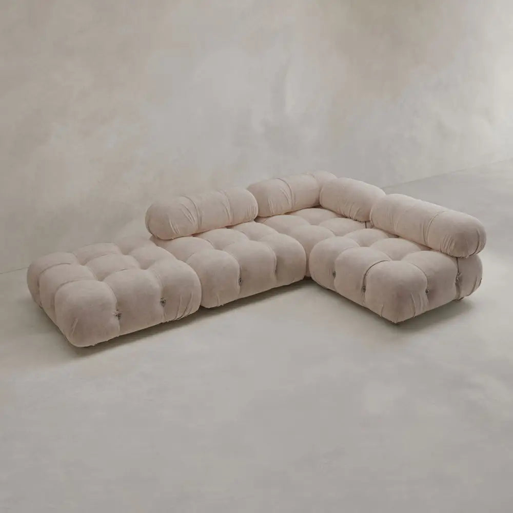 The Belmont Sofa Combination C is a modern, light beige modular sectional with tufted, marshmallow-like curves, rounded edges, and low backrests, set against plain neutral walls and floors.