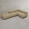 The Belmont Sofa Combination C is a modern beige sectional with tufted cushions and soft, curved lines in an L-shape, set in a minimalist room with light gray walls and flooring.