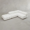 The Belmont Sofa Combination C is a modern white sectional with classic tufted cushions and marshmallow-like curves, featured in a minimalist room with a plain light gray wall and floor.