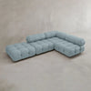 The Belmont Sofa Combination C, a modern light blue tufted sectional with marshmallow-like curves and rounded backrests, sits on a smooth light gray floor against a neutral wall—an iconic classic reimagined for today’s spaces.
