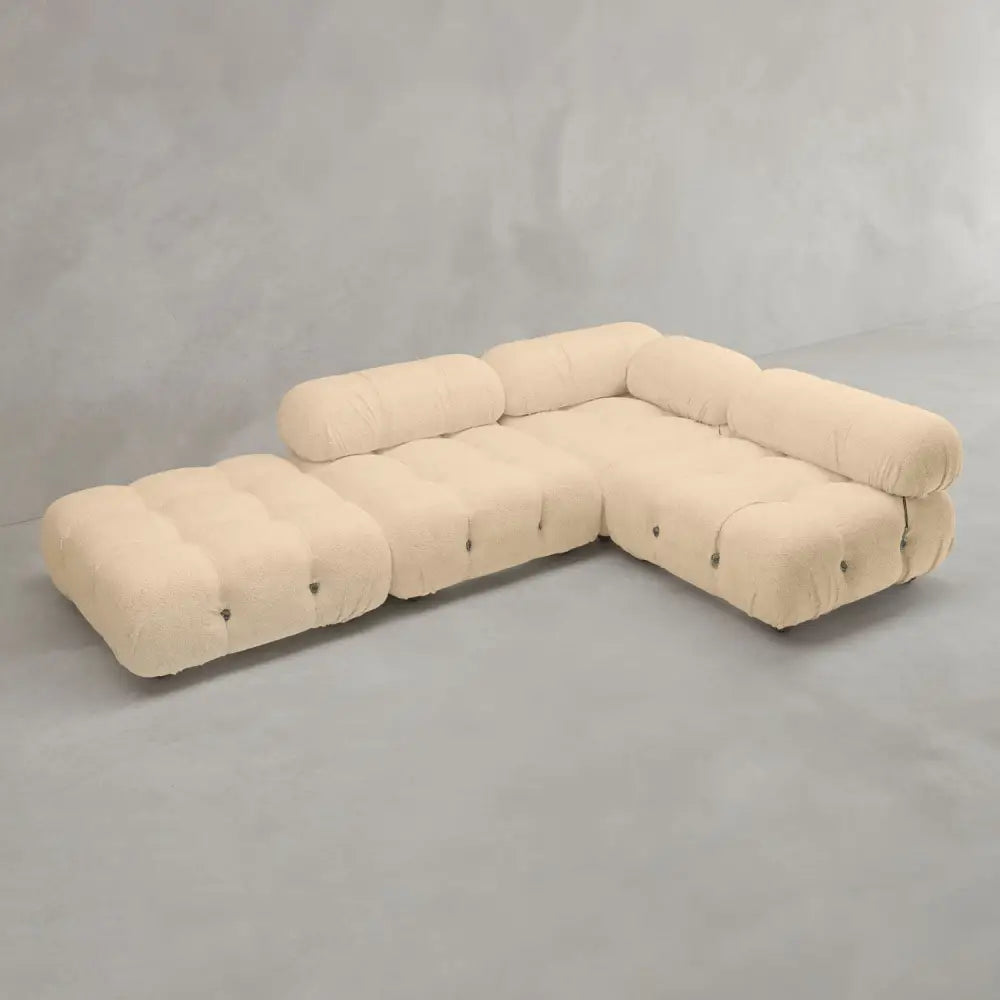 The Belmont Sofa Combination C is a modern, modular sectional with beige tufted fabric and rounded, marshmallow-like cushions, arranged in an L-shape on a plain gray floor against a light gray wall.