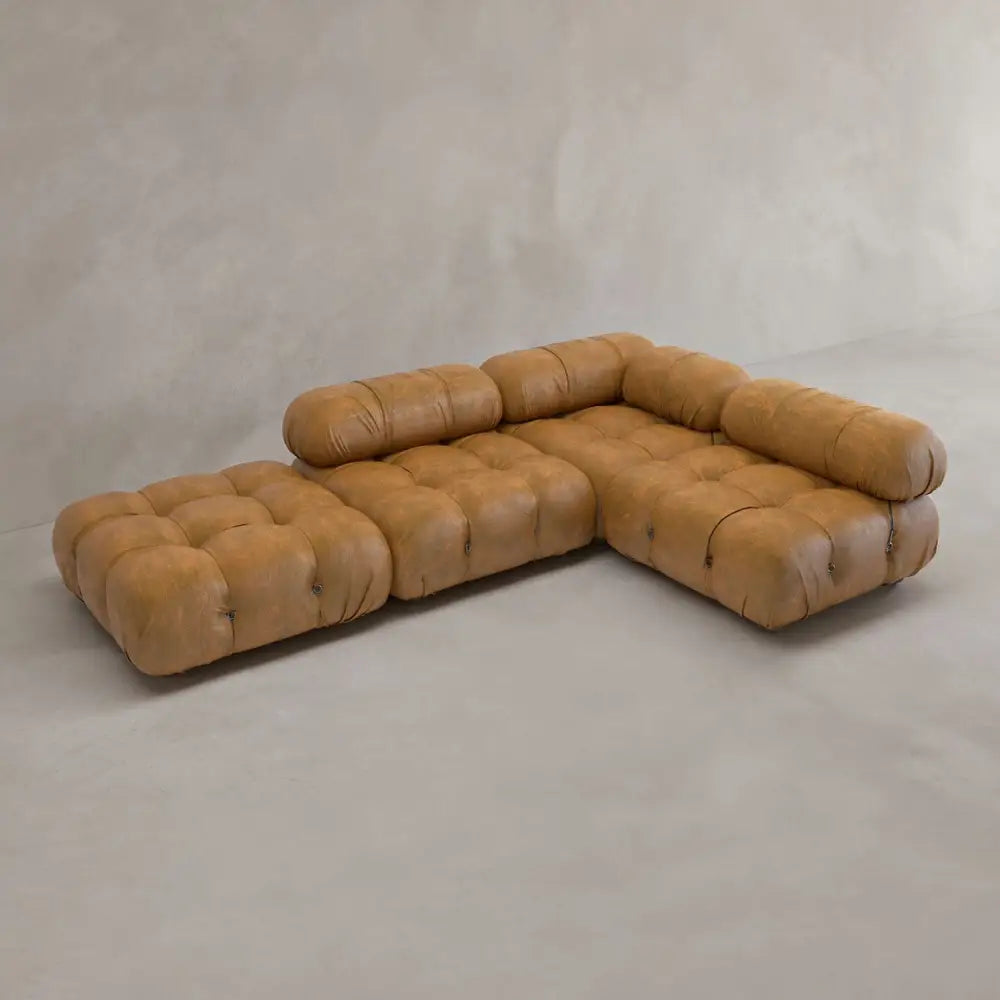 The Belmont Sofa Combination C is a brown, tufted modular sectional with marshmallow-like curves, low seat, and rounded cushions in an L-shape on a light floor against a neutral beige wall.