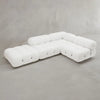 The Belmont Sofa Combination C, a modern modular white sectional with tufted cushions and marshmallow-like curves, sits on a light gray concrete floor against a plain gray wall.