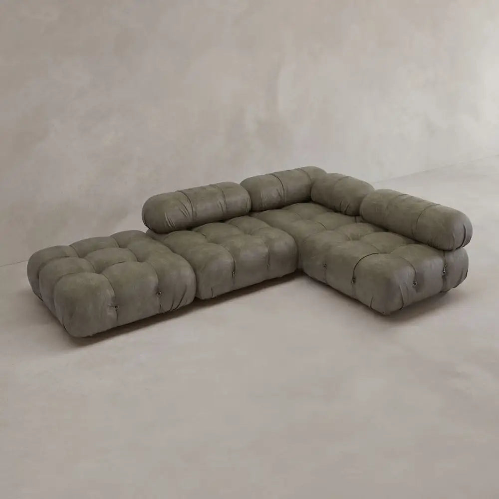 The Belmont Sofa Combination C features a modern, modular L-shaped design with tufted olive-green cushions, low backs, and marshmallow-like curves set against a light-toned minimalist backdrop.