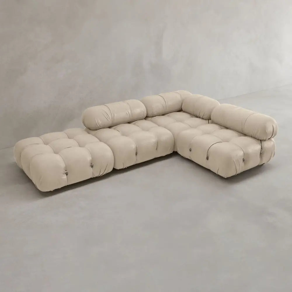 The Belmont Sofa Combination C is a modern, beige L-shaped sectional with tufted upholstery, marshmallow-like curves, and rounded cushioned arm and backrests, displayed against a plain light gray background.