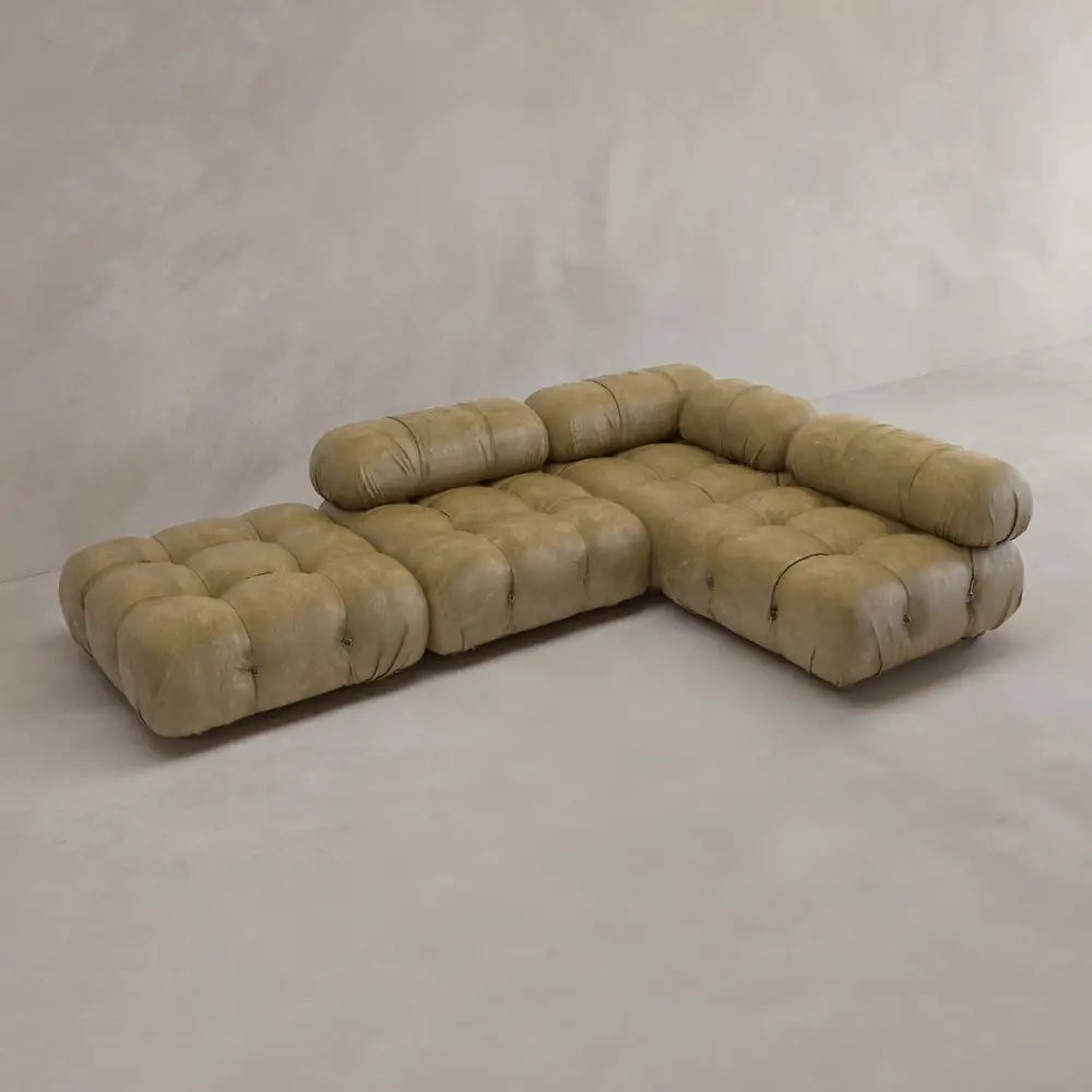 The Belmont Sofa Combination C is a modular, vintage-style sectional with tufted light brown leather cushions, low backrests, and marshmallow-like curves, shown in an empty room with light walls and flooring.