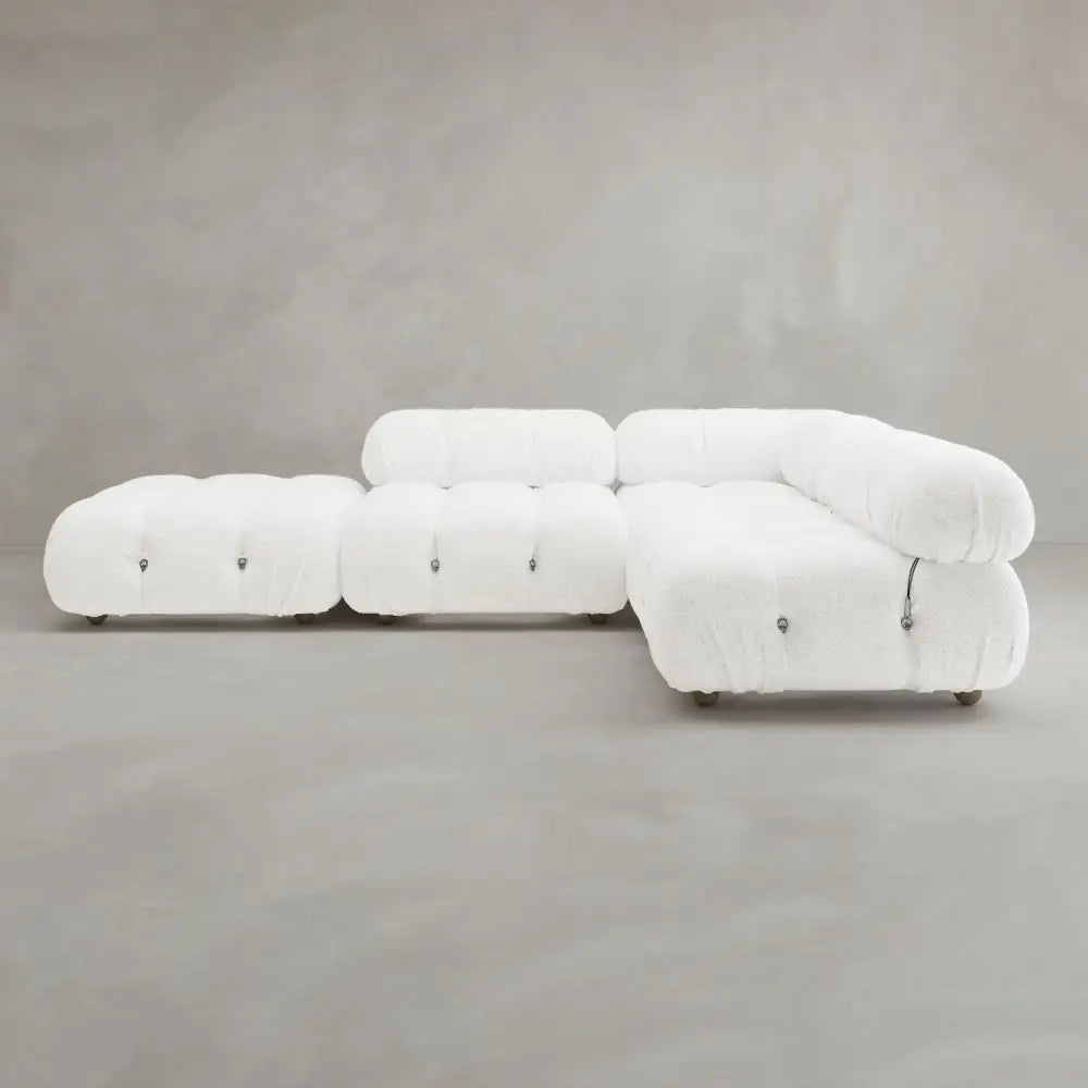 The Belmont Sofa Combination C is a modular white tufted sectional with marshmallow-like curves and rounded edges, highlighting its iconic classic design against a plain gray background.