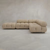 The Belmont Sofa Combination C, a modern beige sectional with tufted cushions and rounded edges, sits on a smooth light gray floor against a neutral gray wall.