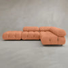 The Belmont Sofa Combination C is a modular orange sofa with classic tufted, marshmallow-like curves and an L-shaped design, set on a smooth light gray floor against a plain gray wall.