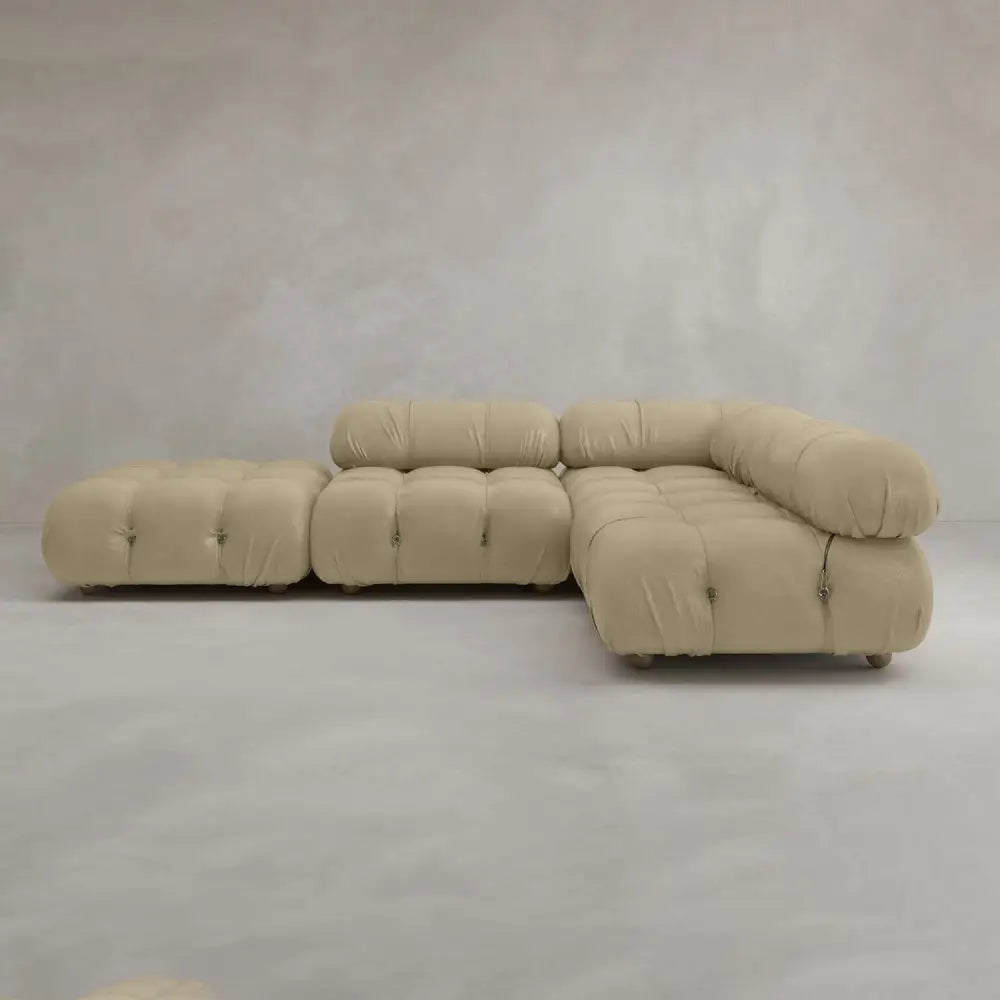 The Belmont Sofa Combination C is a modern, beige sectional with tufted details, marshmallow-like curves, rounded edges, modular design, and low seating, shown against a plain light grey background.