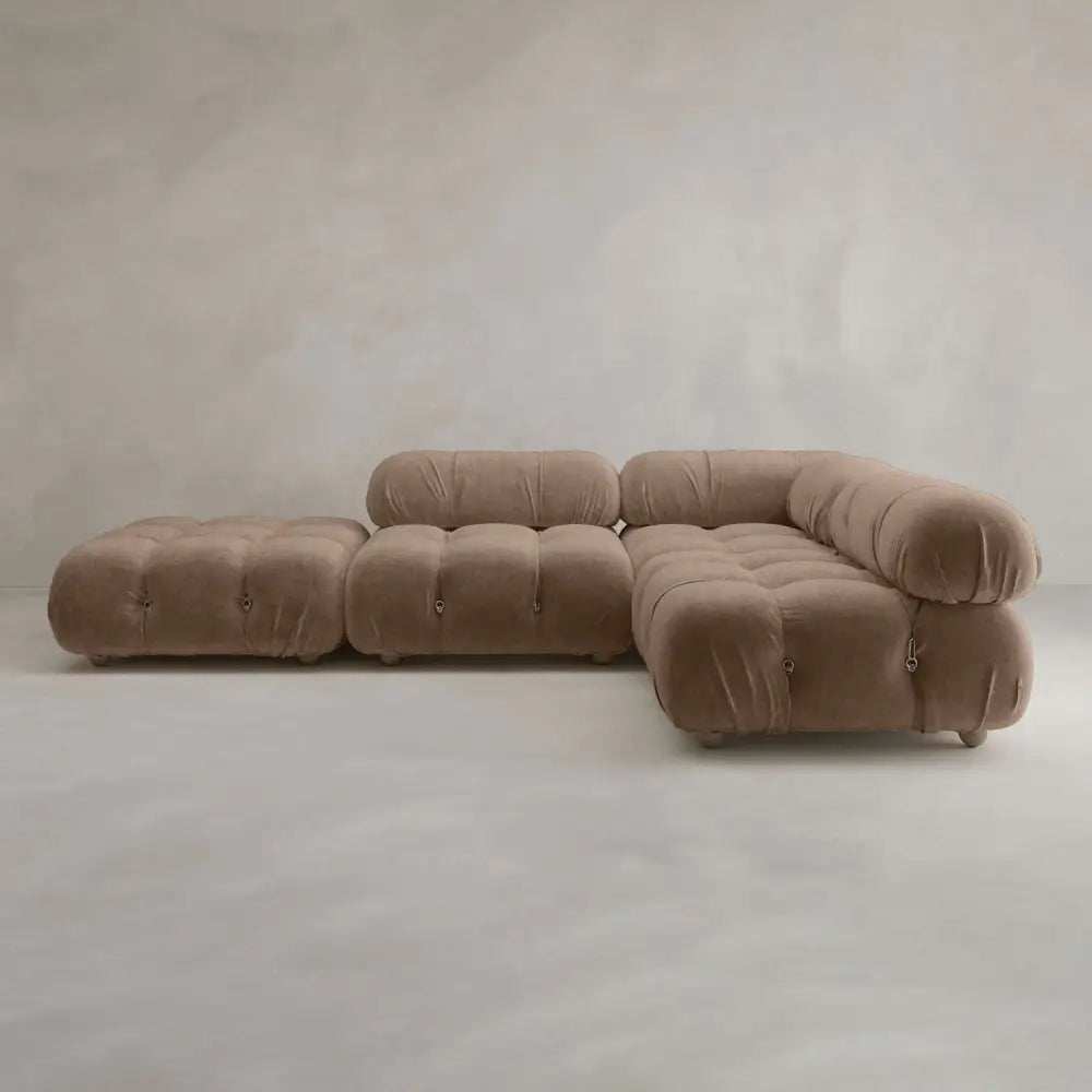 The Belmont Sofa Combination C—a modular, tufted brown sofa with plush, marshmallow-like curves—rests against a plain, light gray textured wall and floor.