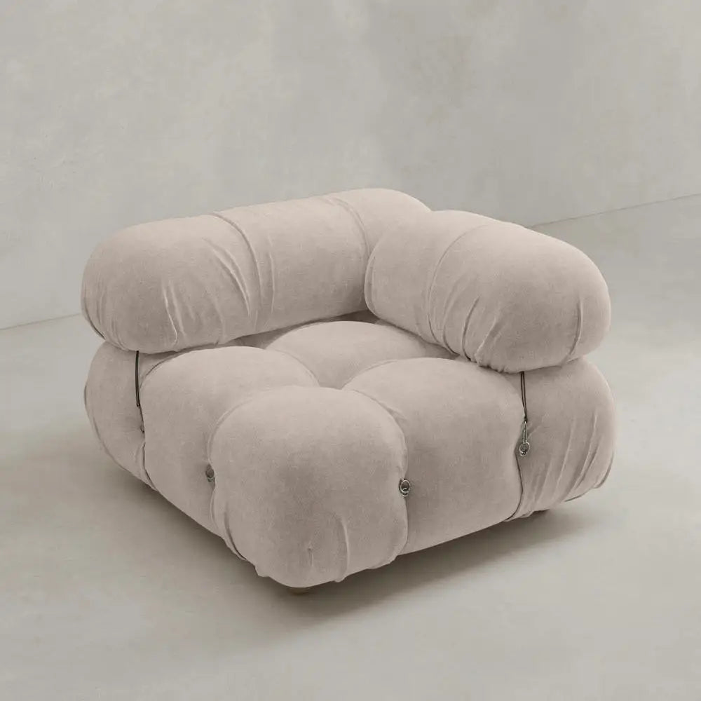 The Belmont Sofa Left Armrest features marshmallow-like curves, plush rounded cushions, tufted buttons, and visible metal fasteners on the sides in light beige upholstery, all set against a plain light-colored background.