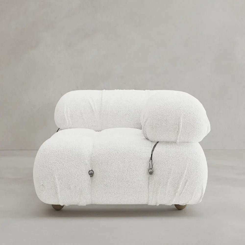The Belmont Sofa Left Armrest features a plush, modern white design with marshmallow-like curves, tufted upholstery, minimalist metal accents, and modular elements. It is shown against a plain light gray background.