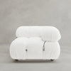 The Belmont Sofa Left Armrest is a modern, armless white lounge chair with plush textured fabric, rounded cushions, visible black cord details, and a modular design; displayed on a plain light gray background.