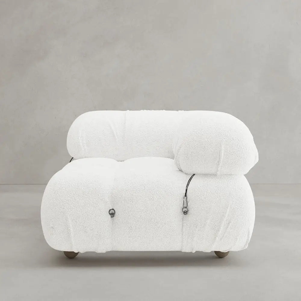 The Belmont Sofa Left Armrest is a modern, armless white lounge chair with plush textured fabric, rounded cushions, visible black cord details, and a modular design; displayed on a plain light gray background.