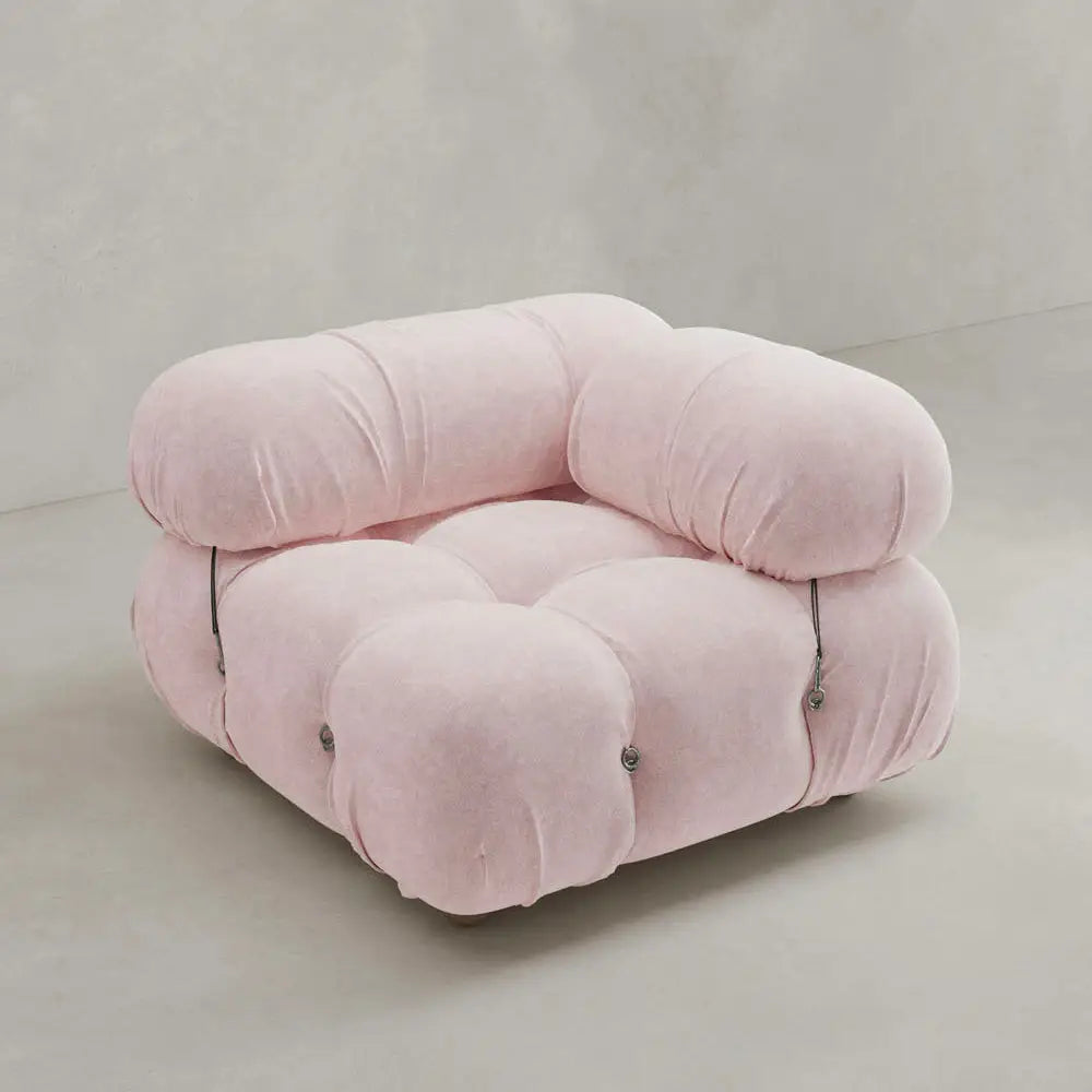 A plush, light pink Belmont Sofa Left Armrest features oversized, rounded cushions and visible tufted buttons, evoking a cloud-like feel and set against a plain, light-colored background.