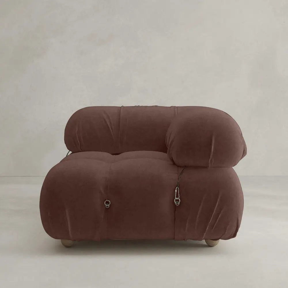 The Belmont Sofa Left Armrest is a modern, plush brown piece with a rounded, puffy design inspired by cloud-like sofas. It features soft upholstery, metal clip accents, and is set against a plain light gray background.
